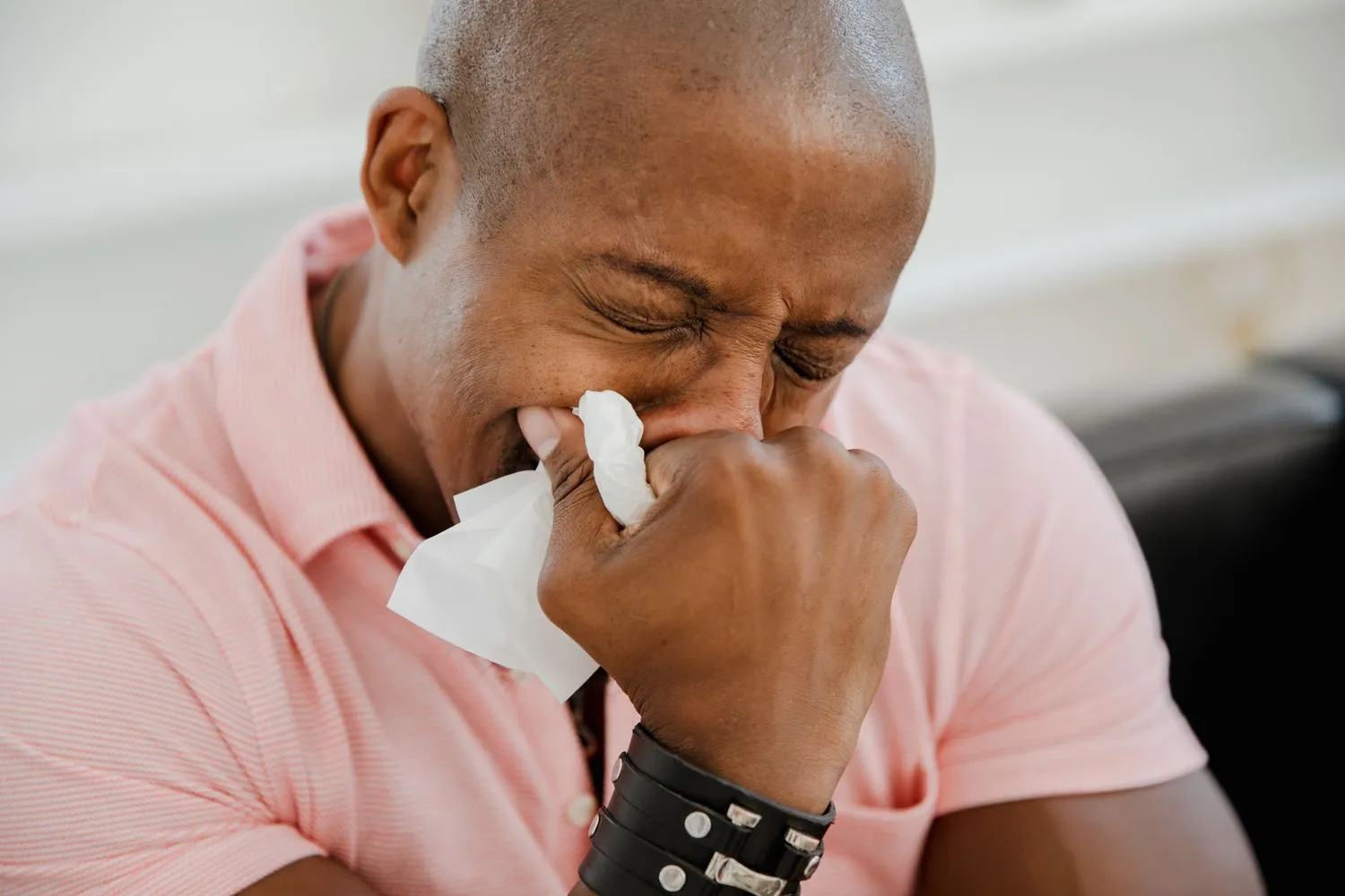 Man sneezing into a tissue from seasonal allergy symptoms