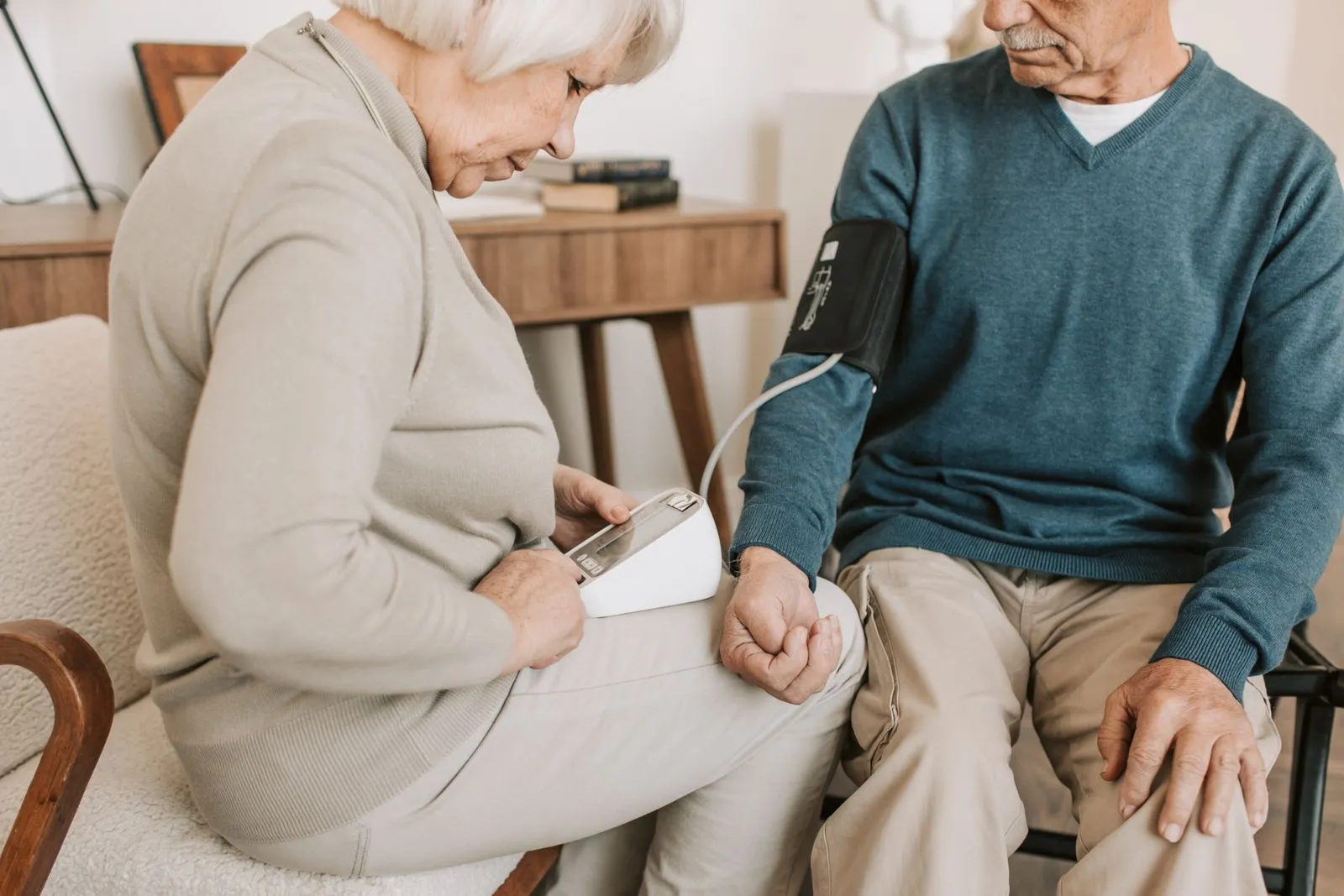 Older couple measuring blood pressure at home with a digital monitor