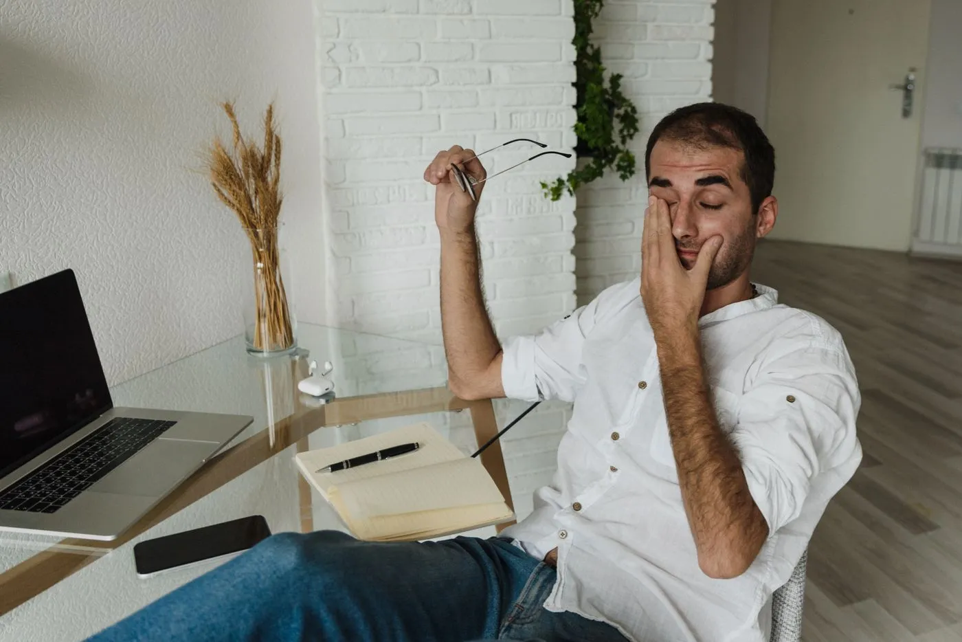 iGenics Reviews: Does This Eye Supplement Work? 2 Tired man rubbing his strained eyes at a desk, glasses in hand