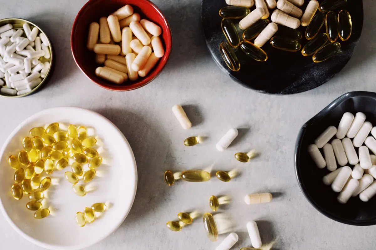 An assortment of multivitamin capsules and softgels in bowls
