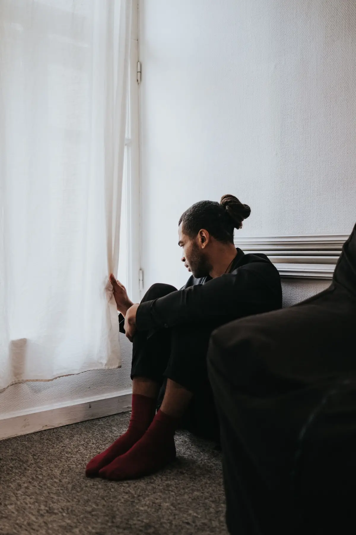 PrimalTRT Reviews: Do These Primal TRT Male Vitality Gummies Work? 2 Man sitting low-energy by a window, frustrated with flagging drive