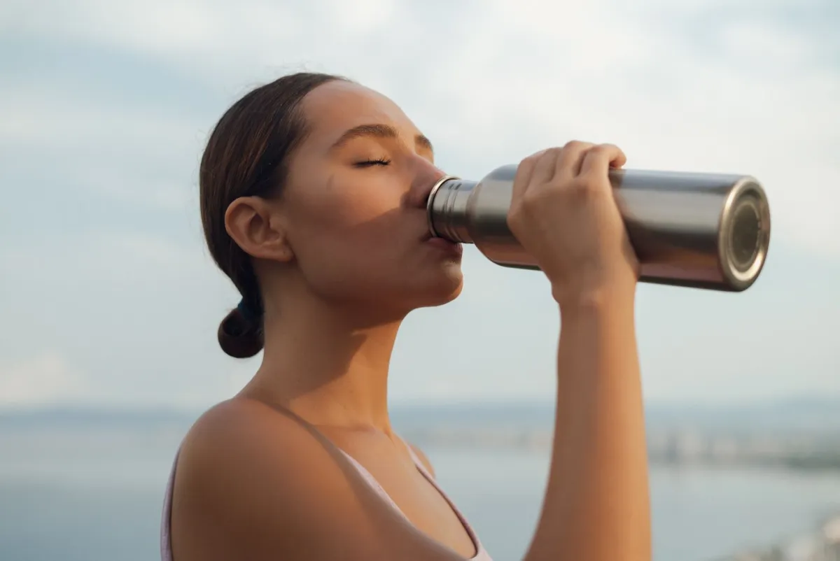 A healthy woman drinking water outdoors